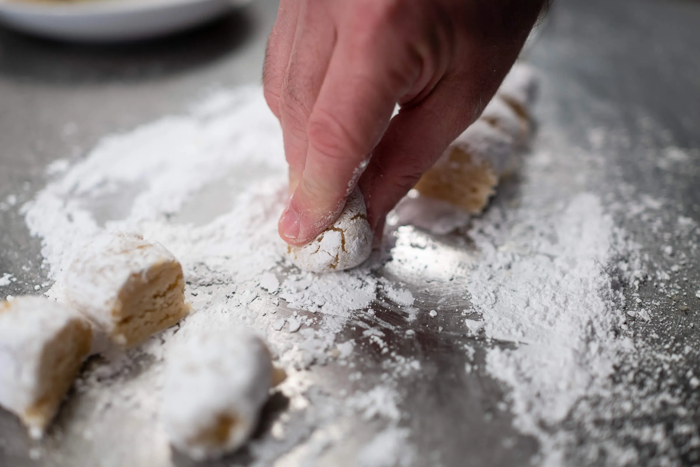 Zwei geformte Mandelkekse, mit Puderzucker bestäubt und bereit zum Backen