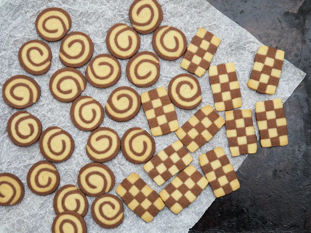 Zweifarbiges Schwarz-Weiß-Gebäck in verschiedenen Formen auf einem Backblech