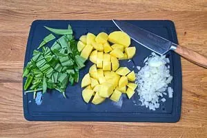 Zwiebeln, Kartoffeln und frischer Bärlauch werden sorgfältig für die Suppe geschnitten