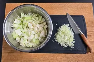 Zwiebeln und Weißkohl in Würfel geschnitten auf einem Holzbrett