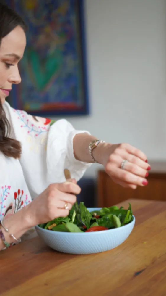 Frau isst einen Salat und schaut dabei auf die Uhr