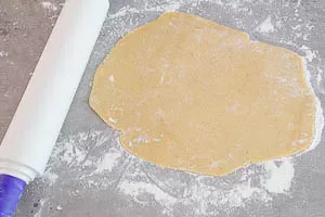 Plätzchenteig auf einer bemehlten Arbeitsfläche ausrollen