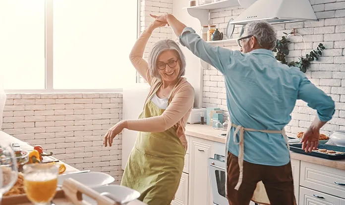 Älteres Paar tanzt glücklich in der Küche als Zeichen sorgloser Pension
