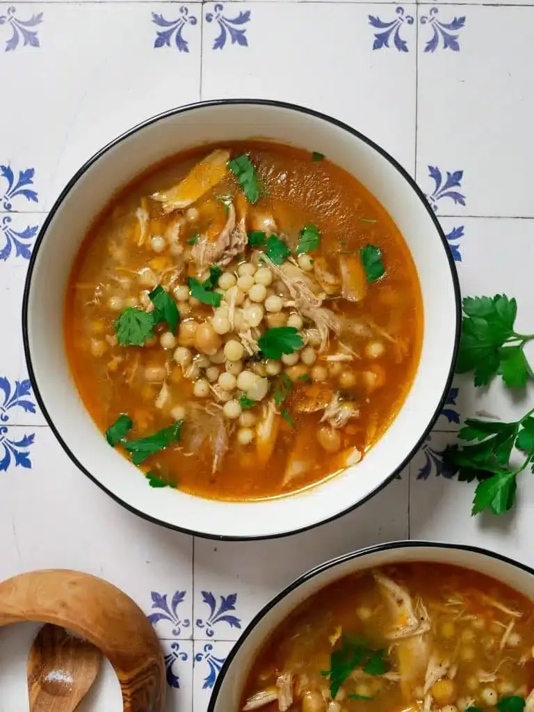 Arabischer Hühnereintopf Moghrabieh mit Perl-Couscous in einer Schüssel