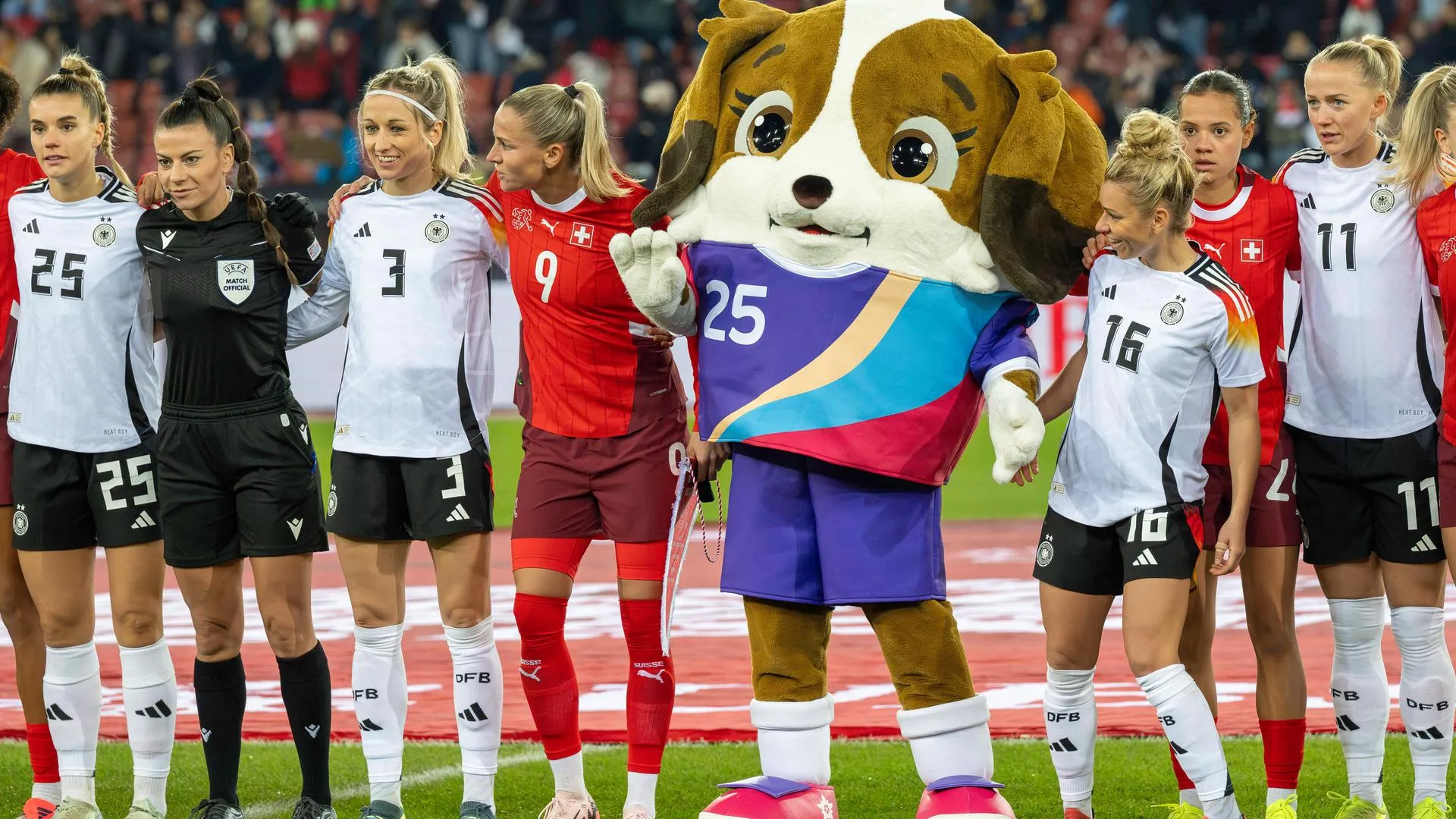 Das Maskottchen Maddli mit Spielerinnen der deutschen und Schweizer Frauen-Nationalmannschaft.