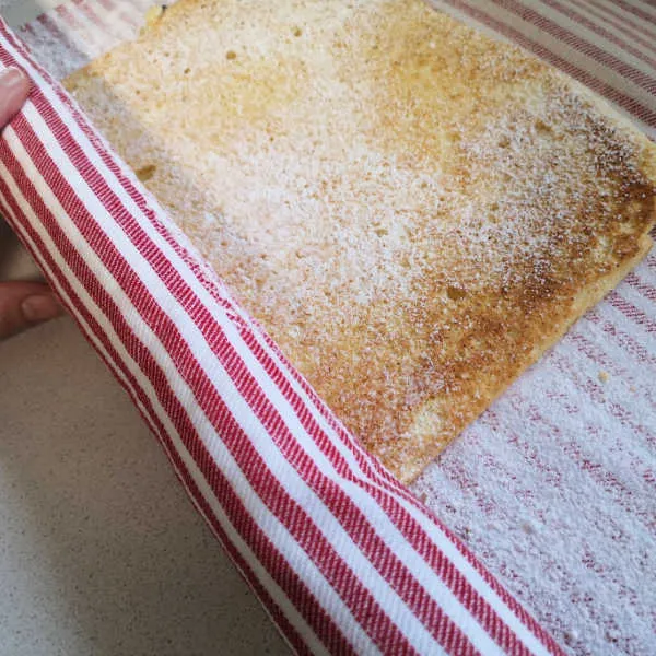 Den warmen Biskuitboden vorsichtig mit einem Geschirrtuch aufrollen