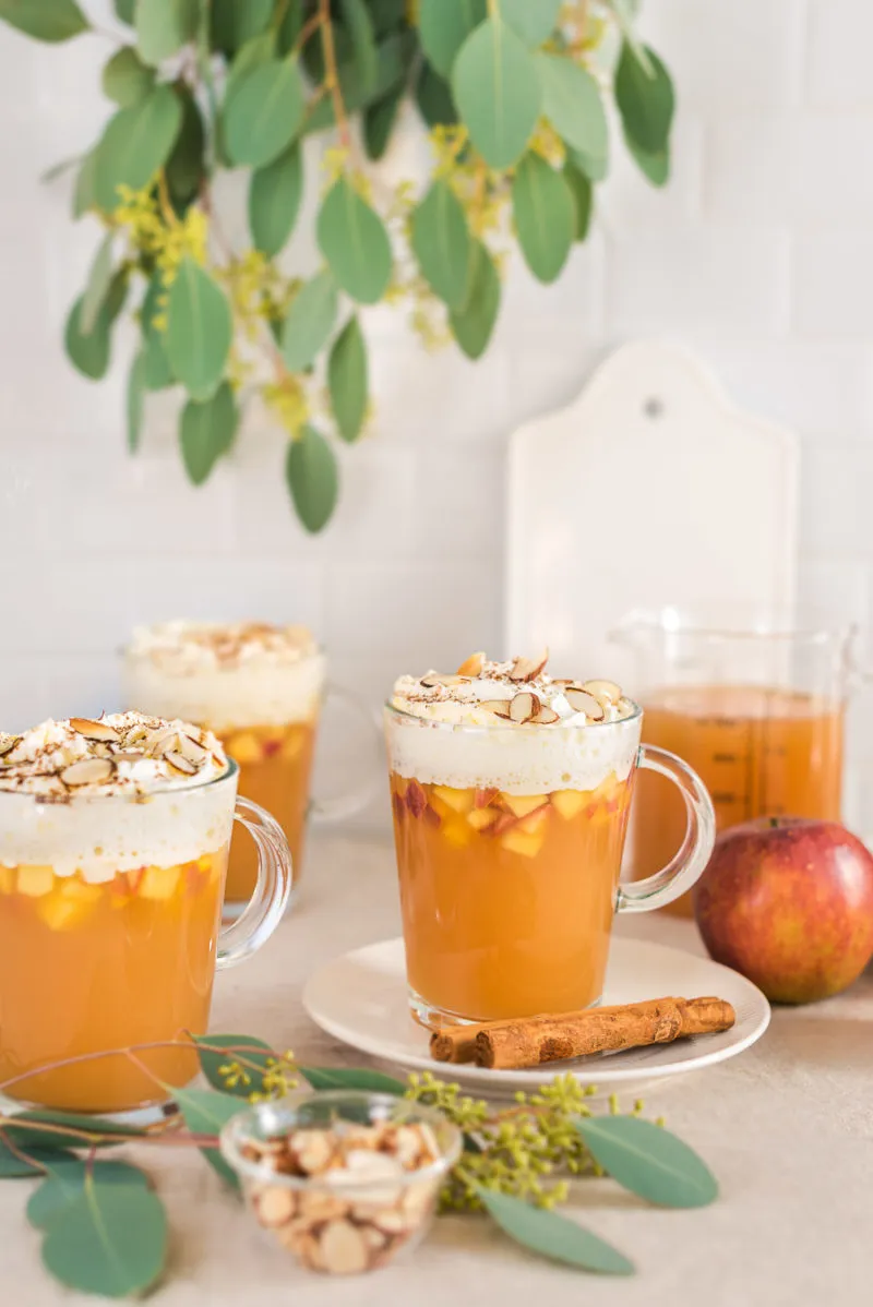 Ein Glas Bratapfelpunsch mit Sahne und Apfelstücken