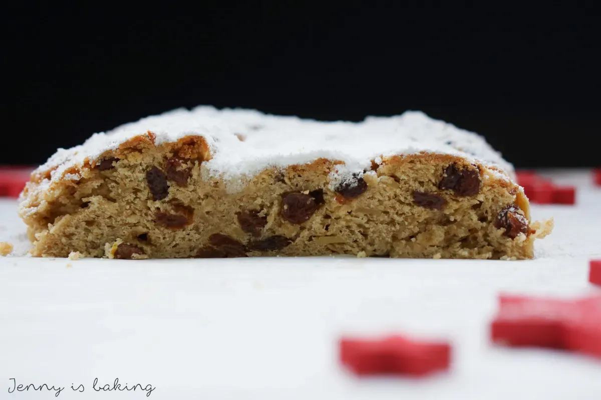 Ein großes Stück angeschnittener Weihnachtsstollen mit Rosinen und Puderzucker