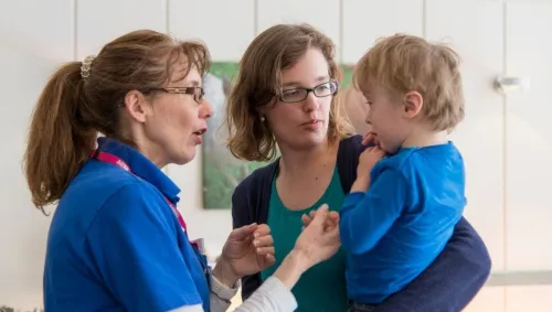 Ein Mitglied des Pflegeteams kümmert sich um ein Kind im Rollstuhl