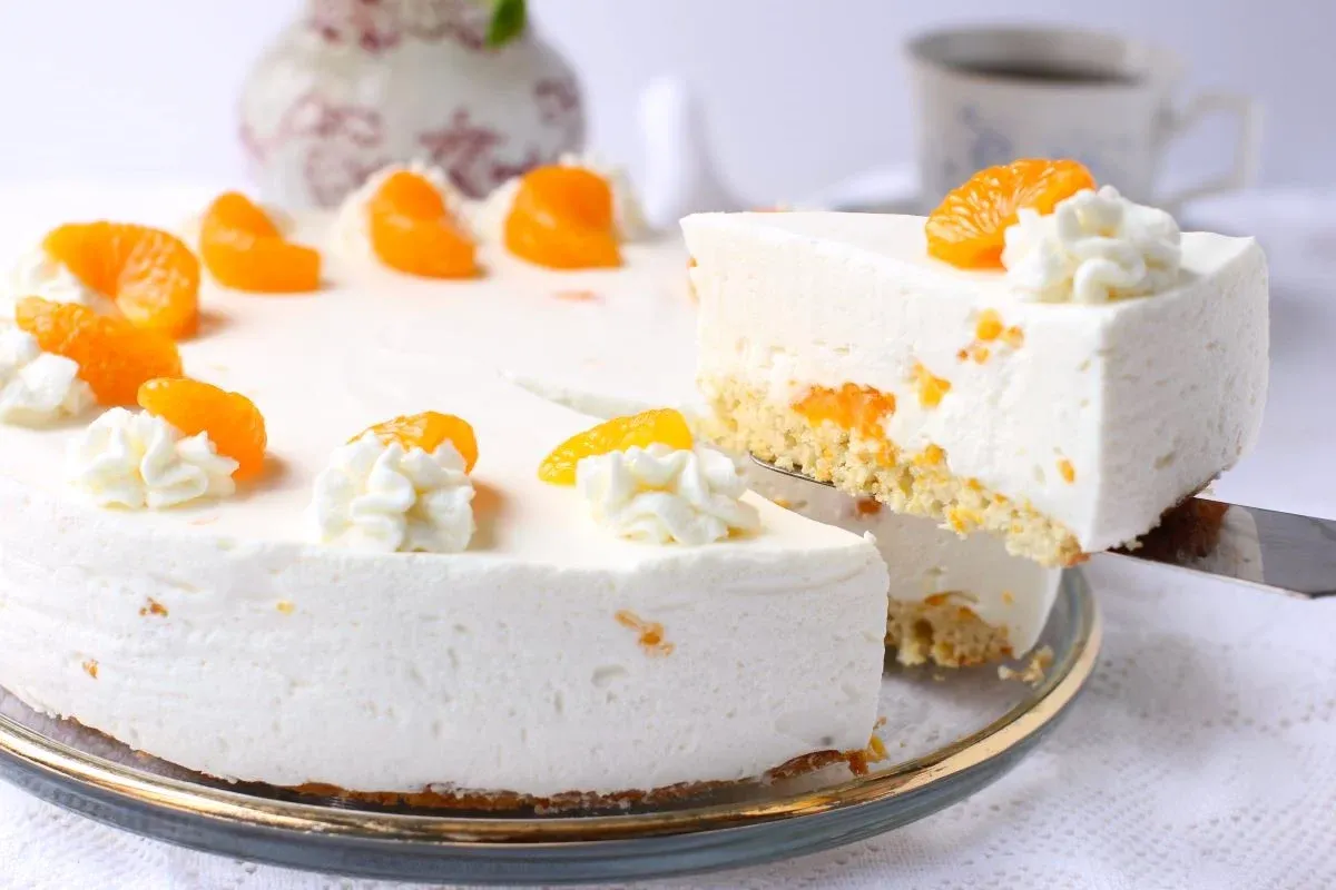 Ein Stück Mandarinen-Sahnetorte aus der Torte heben.