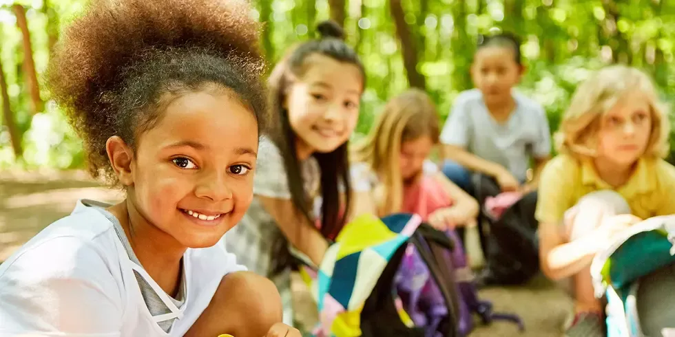 Eine Gruppe junger Schülerinnen und Schüler bei einem Ausflug im Wald.