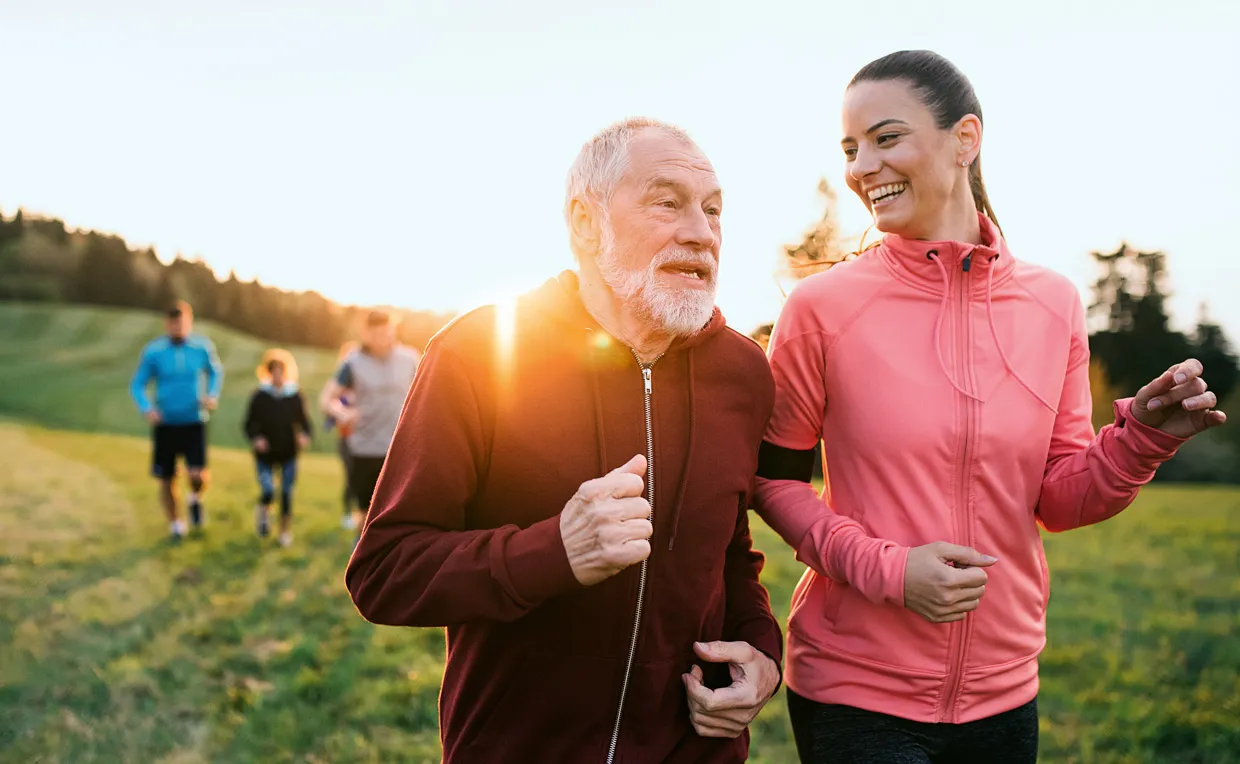 Eine Gruppe unterschiedlicher Läuferinnen und Läufer sind in der Abendsonne in der Natur unterwegs.
