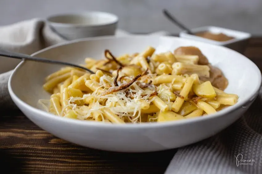 Frisch gekochte Älplermagronen mit geschmolzenem Käse und einem Löffel in einer Pfanne