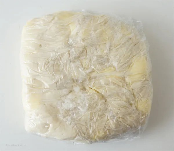 Frisch zubereiteter Blätterteig in Klarsichtfolie gewickelt, bereit zum Kühlen