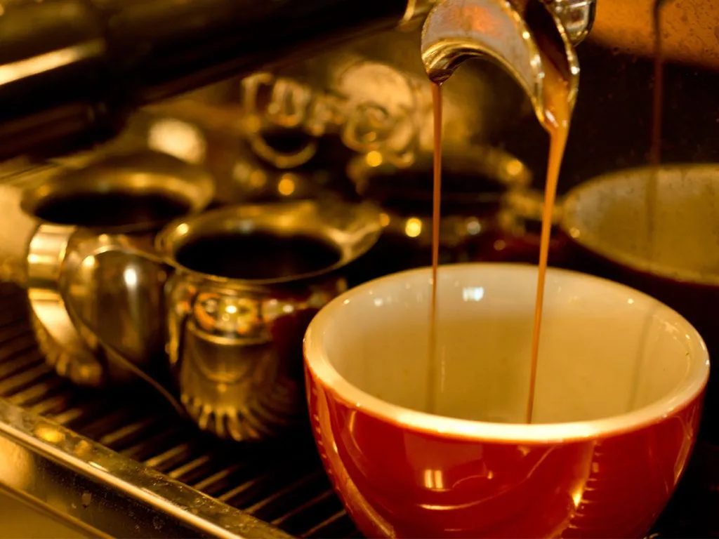 Frisch zubereiteter Espresso, der in eine Tasse gegossen wird