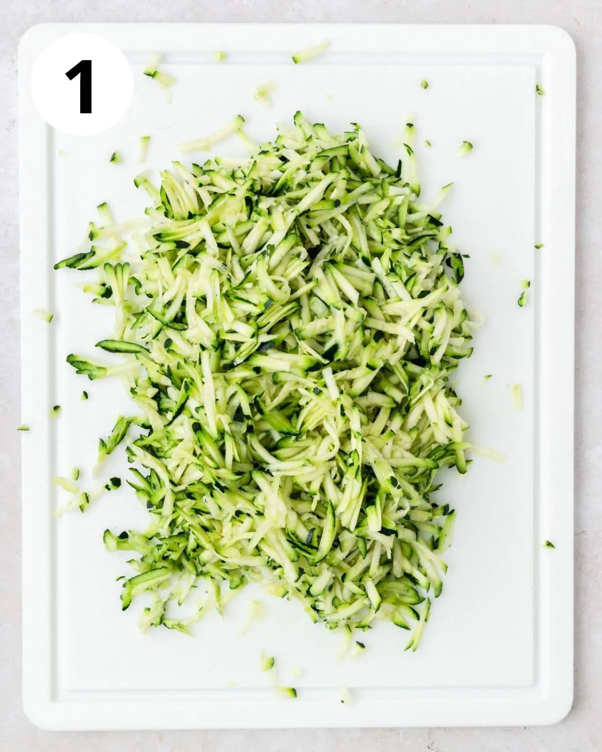 Geriebene Zucchini auf einem Schneidebrett.