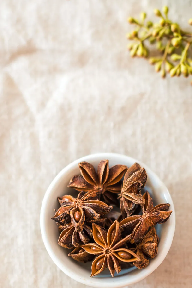 Gläser mit Bratapfelpunsch und frischen Äpfeln im Hintergrund