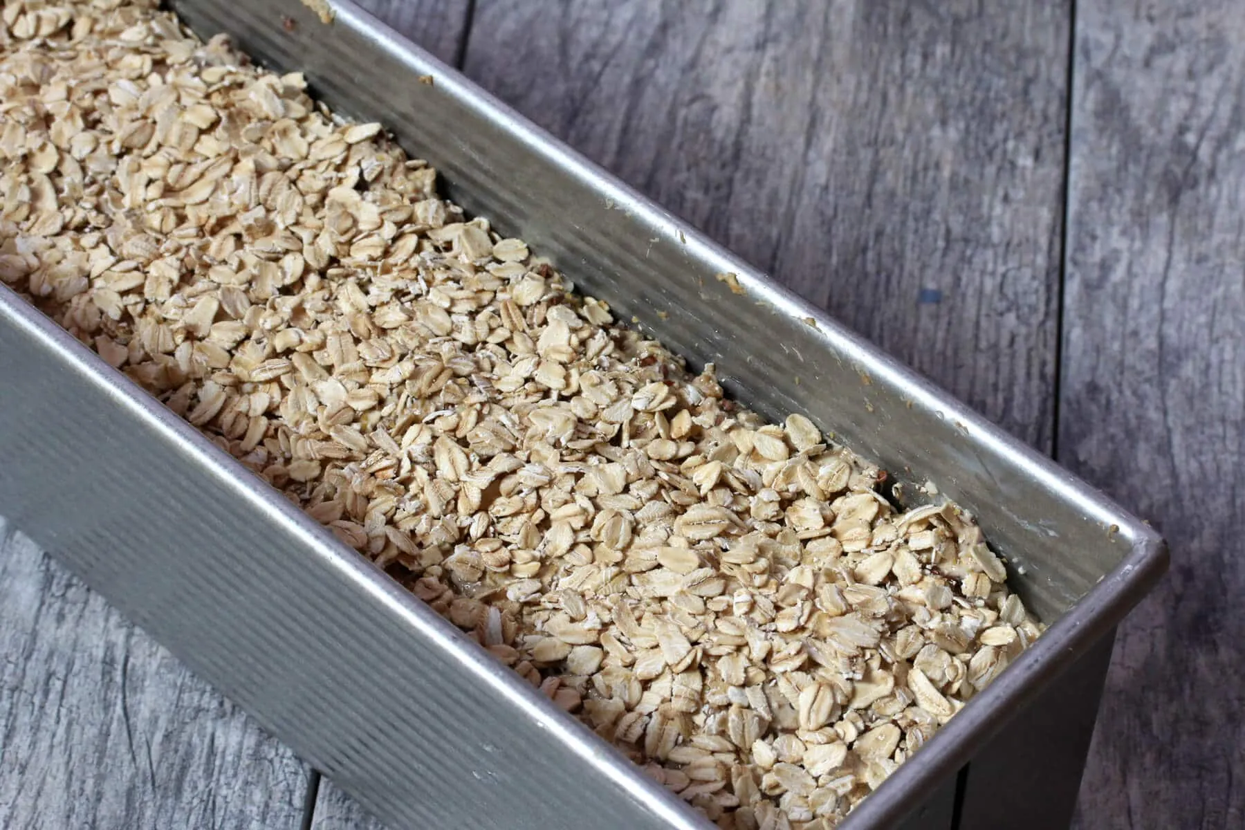 Haferflocken werden auf den Teig in der Form gestreut