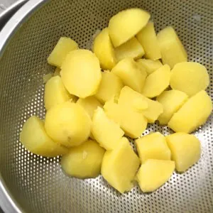 Kartoffeln werden im Sieb geschüttelt, um ihre Oberfläche aufzurauen