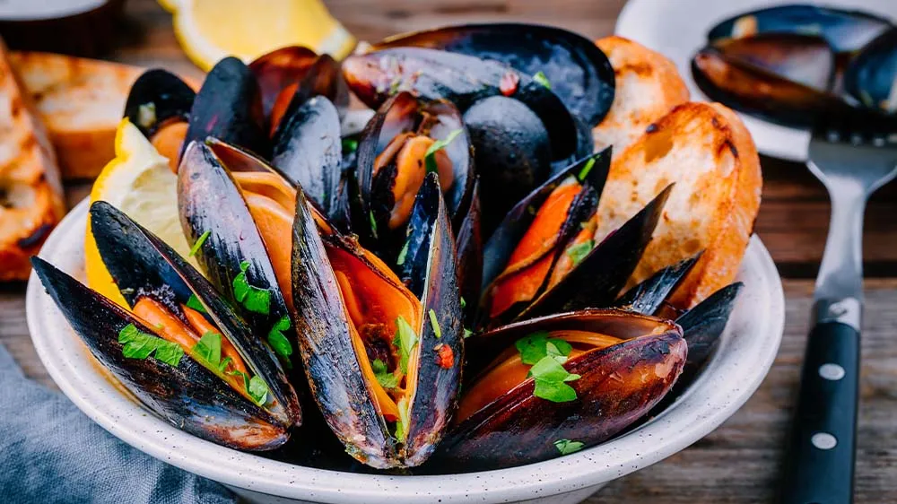 Miesmuscheln mit frischem Baguette in einer Schale serviert