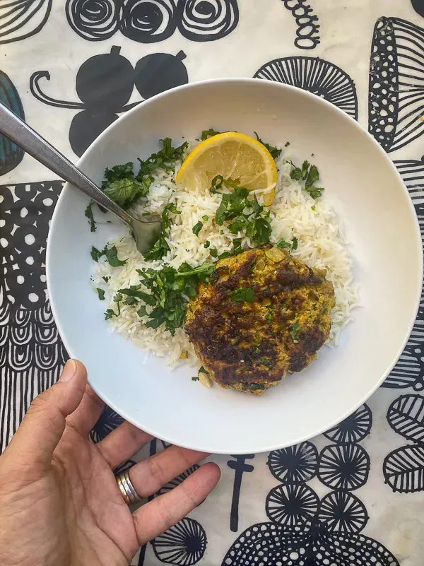 Putenburger serviert mit Reis, Zitrone und frischem Koriander