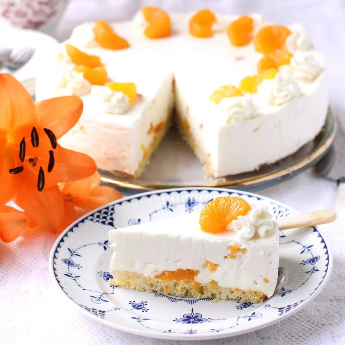 Quadratisches Foto eines Stücks Mandarinen-Sahnetorte mit Kuchen dahinter.