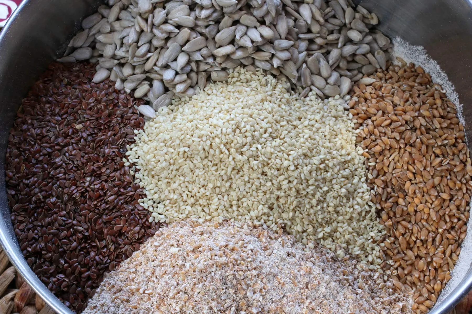 Verschiedene Getreidekörner, Saaten und Mehl in einer großen Rührschüssel