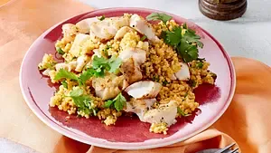 Zarte Fischfiletstücke auf lockerem Koriander-Couscous mit Zitronenecken.