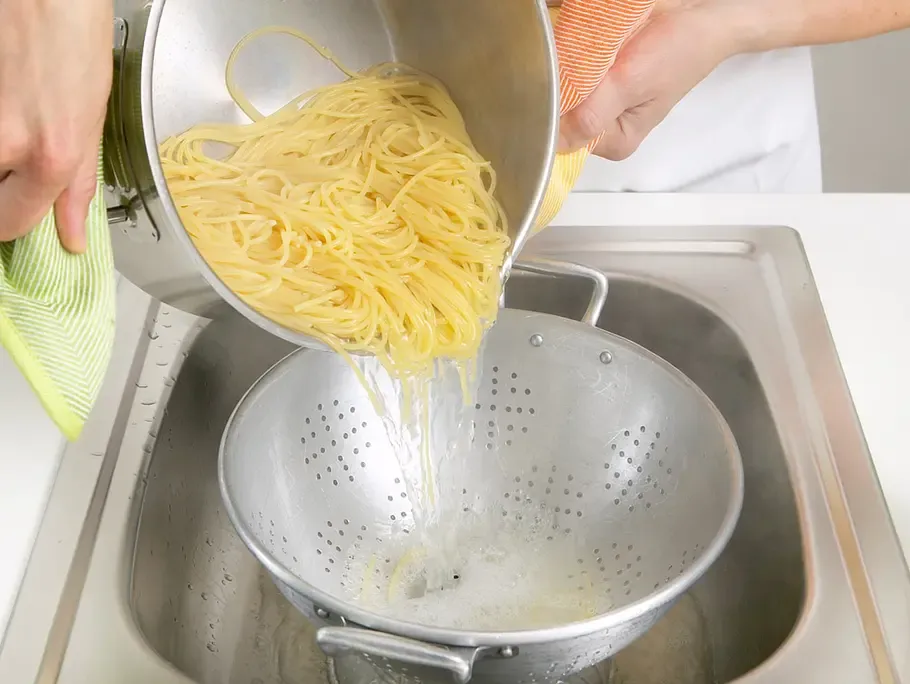 Abgießen frisch gekochter Spaghetti durch ein Sieb