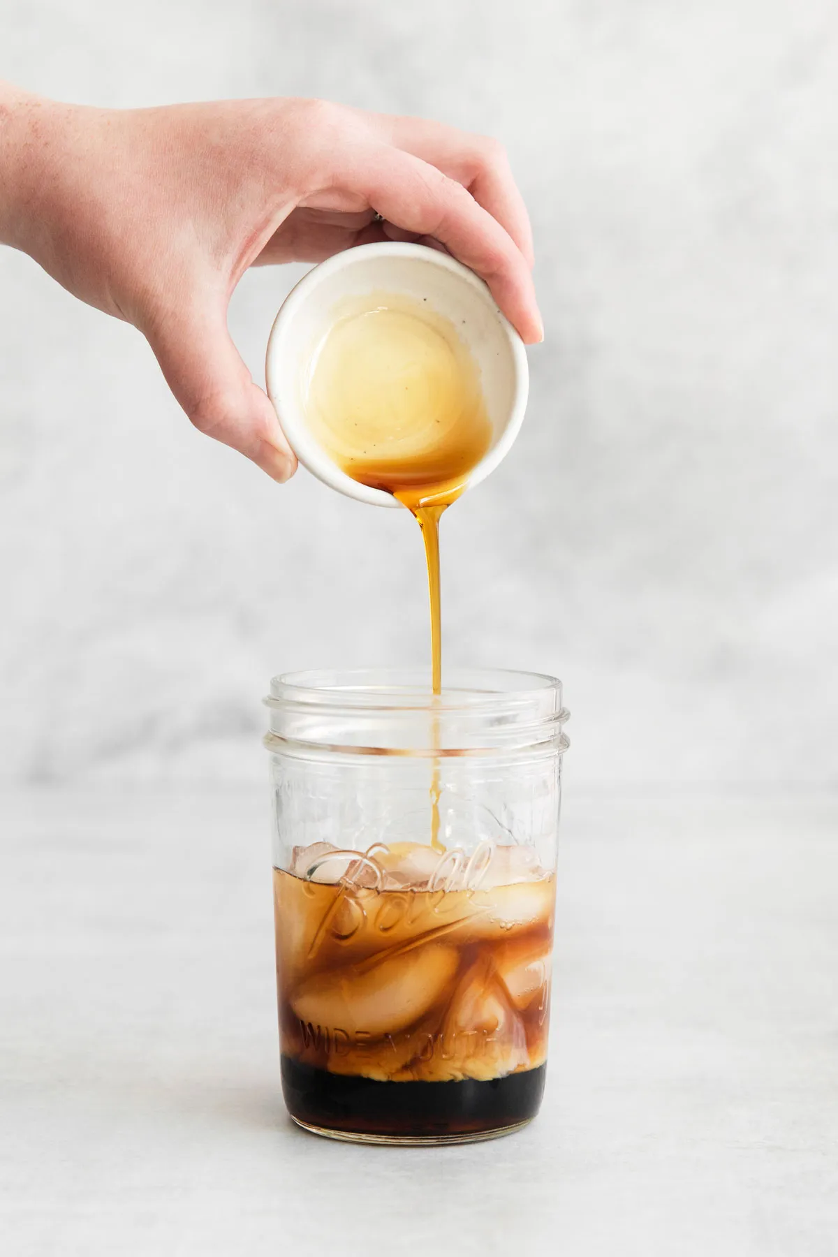 Ahornsirup in ein Glas mit Zutaten gießen