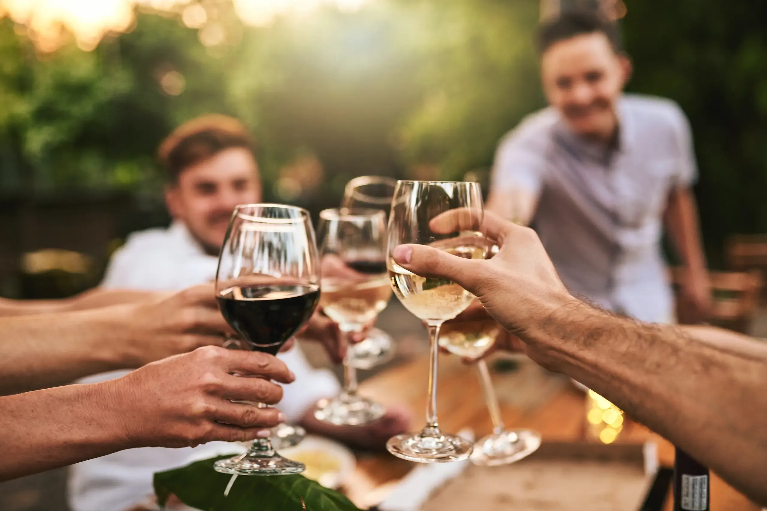 Alkohol? Besser nicht nach der Impfung: Eine Gruppe von jungen Menschen stößt mit einem Glas Wein an.