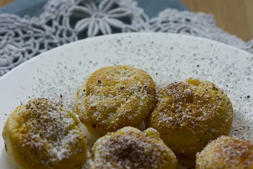 Alt text: Fertig gebackene braune Butter Ebelskiver mit Puderzucker und Kakao bestäubt