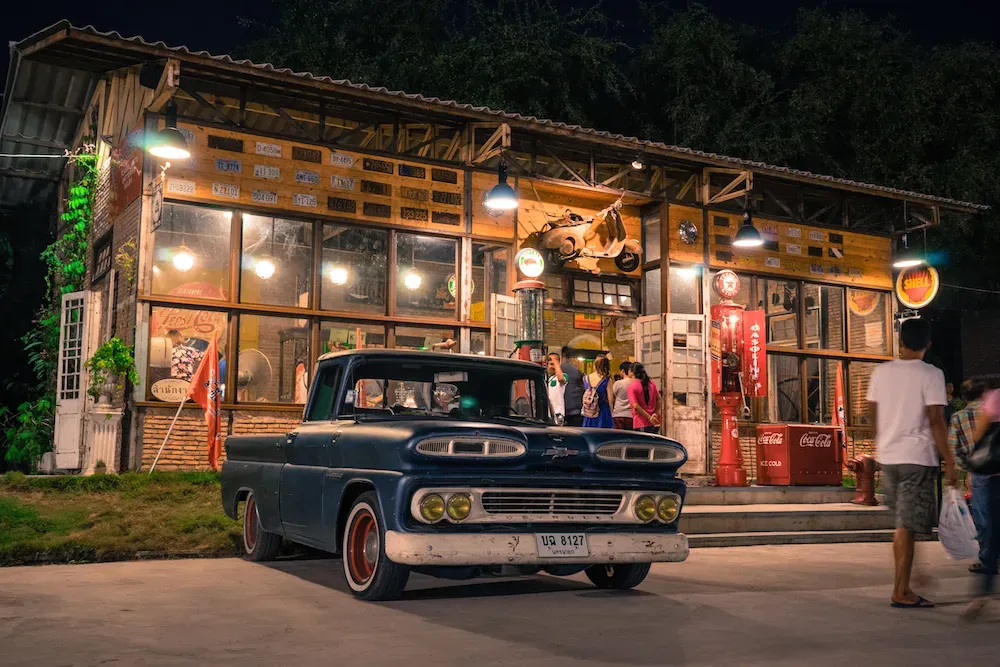 Alte Autos und LKWs vor Lagerhäusern auf dem Talad Rot Fai