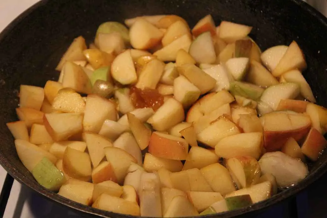 Amaretto wird über die Apfelstücke in der Pfanne gegossen