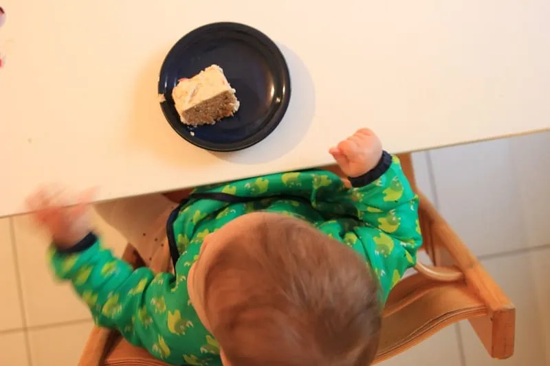 Baby probiert liebevoll zubereiteten zuckerfreien Karottenkuchen in K-Form