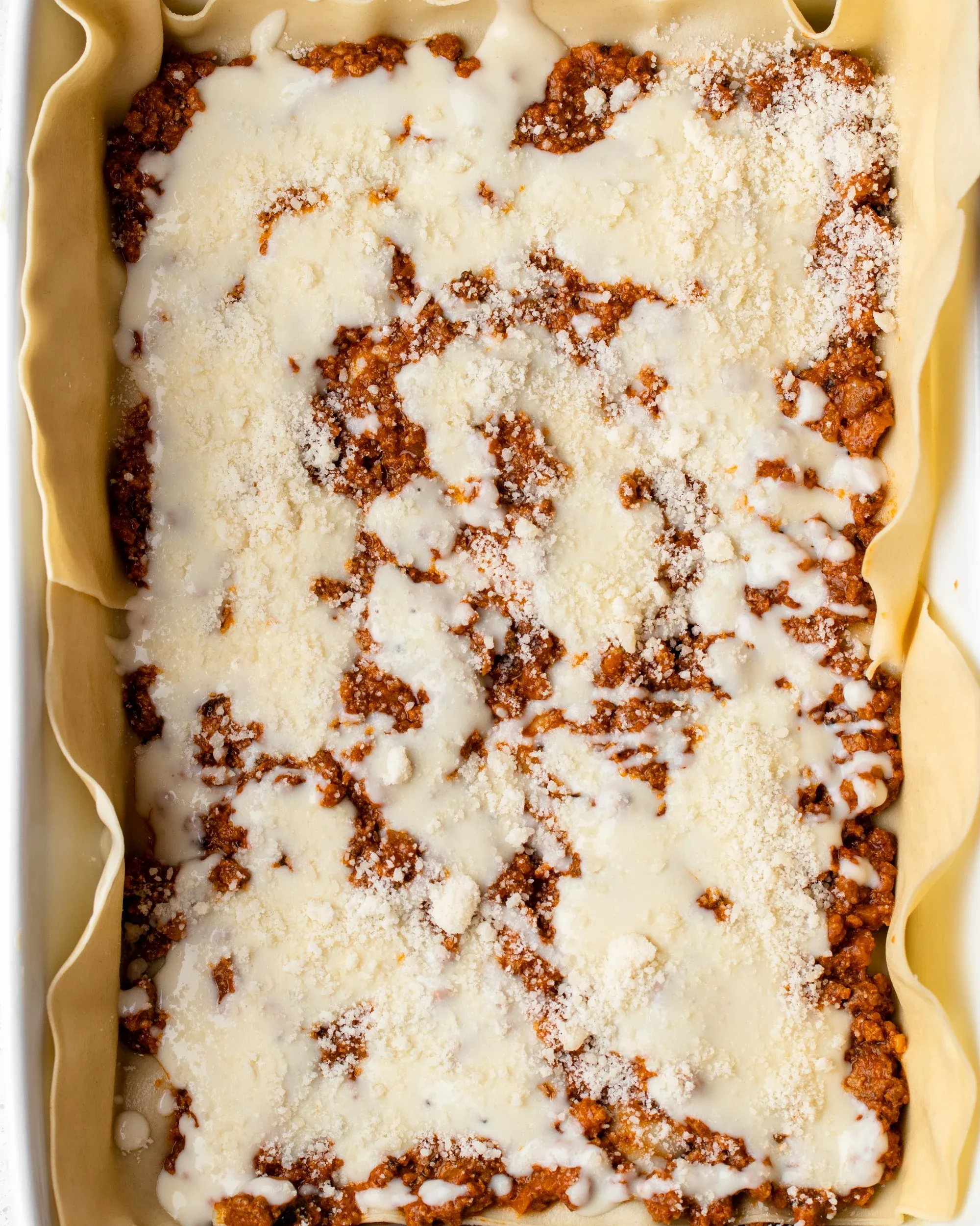 Bestäuben von Parmesankäse auf der Béchamelsauce