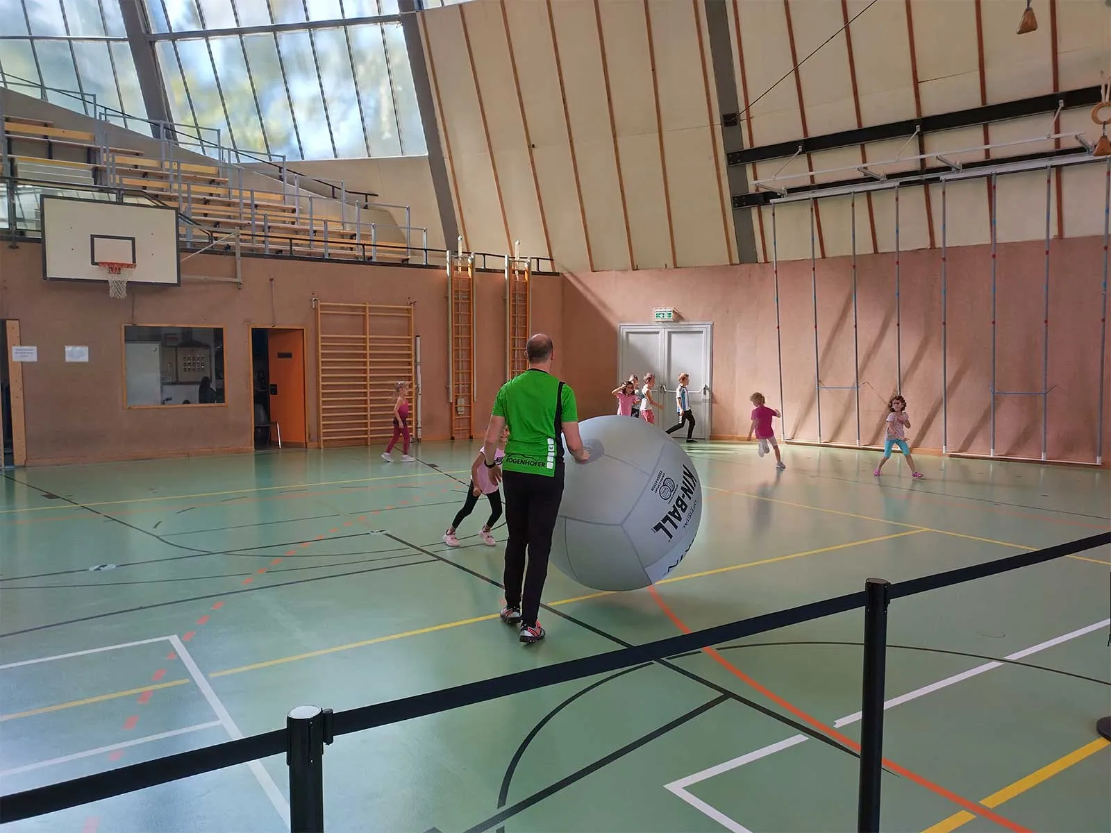 Bezirksgesundheitstag-Favoriten-2023 - Kinder laufen durch den Turnsaal und spielen mit einem großen KIN Ball