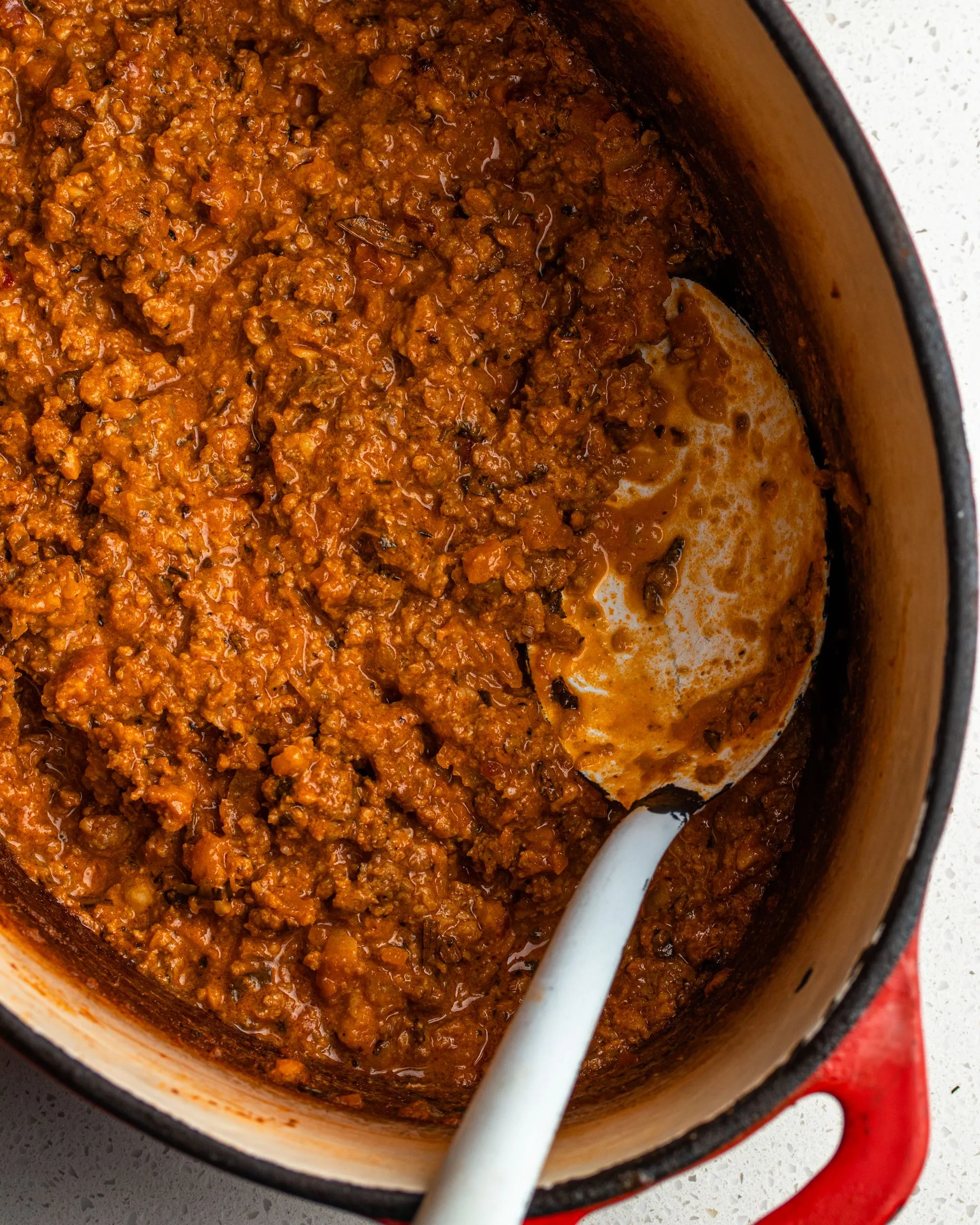Bolognese-Sauce in einem gusseisernen Topf mit einem großen Löffel darin