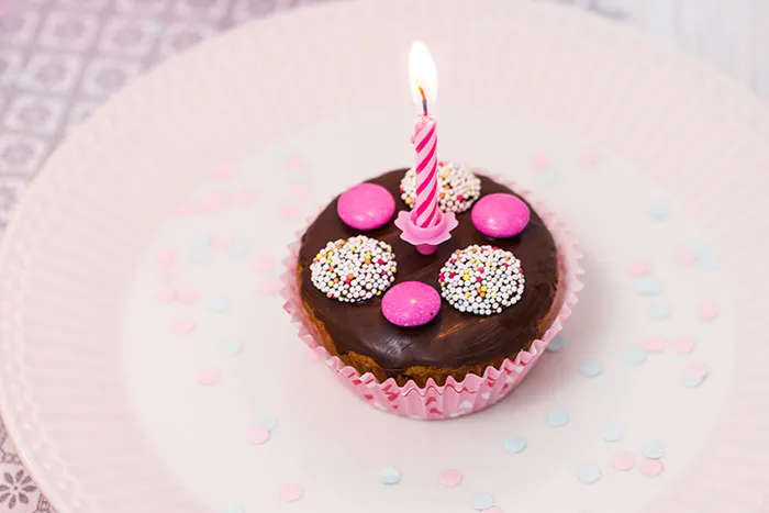 Bunte Zuckerstreusel und Süßigkeiten auf frisch glasierten Muffins