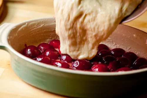 Der Teig wird gleichmäßig über die Pflaumen in der Backform verteilt