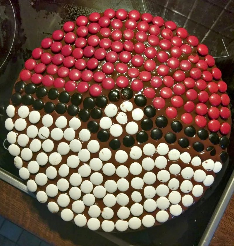 Detailansicht des selbstgemachten Pokéball-Kuchens mit Schokolinsen, bereit zum Verzehr