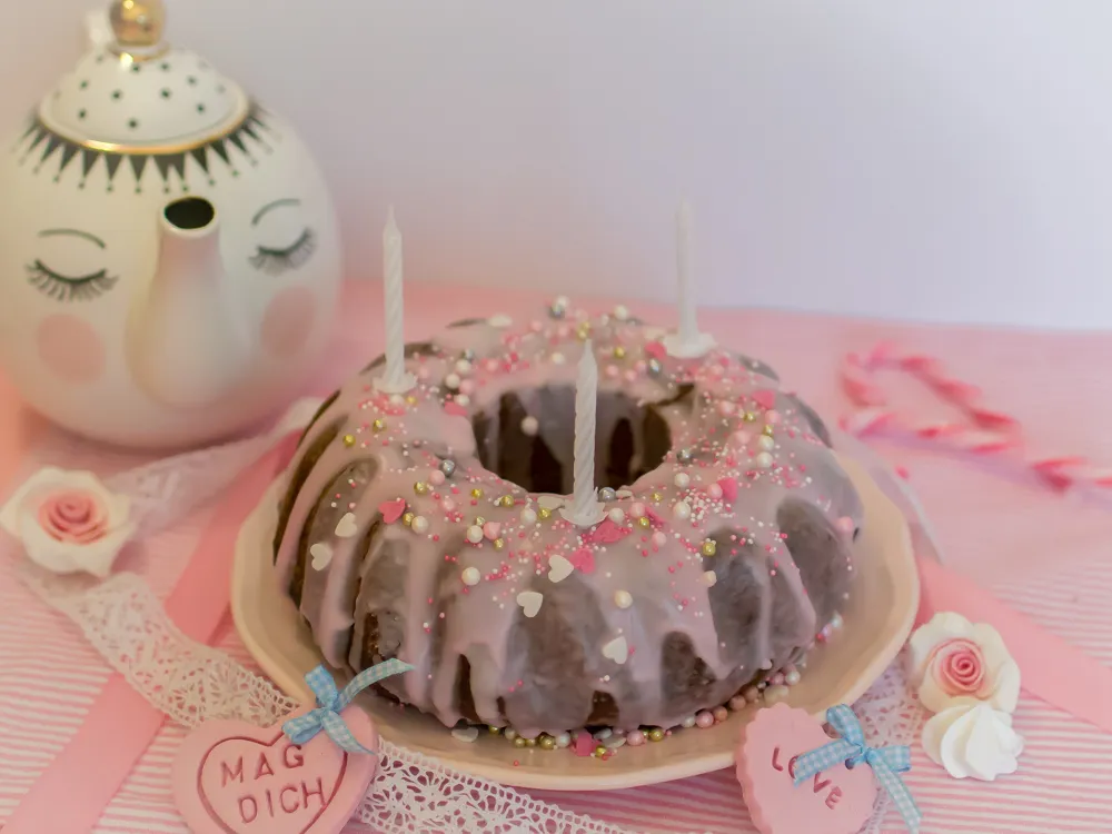 Detailaufnahme eines Zitronenkuchens mit rosa Zuckerguss und Streuseln