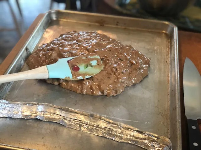 Dicker Keksteig wird auf einem eingefetteten Backblech verteilt.