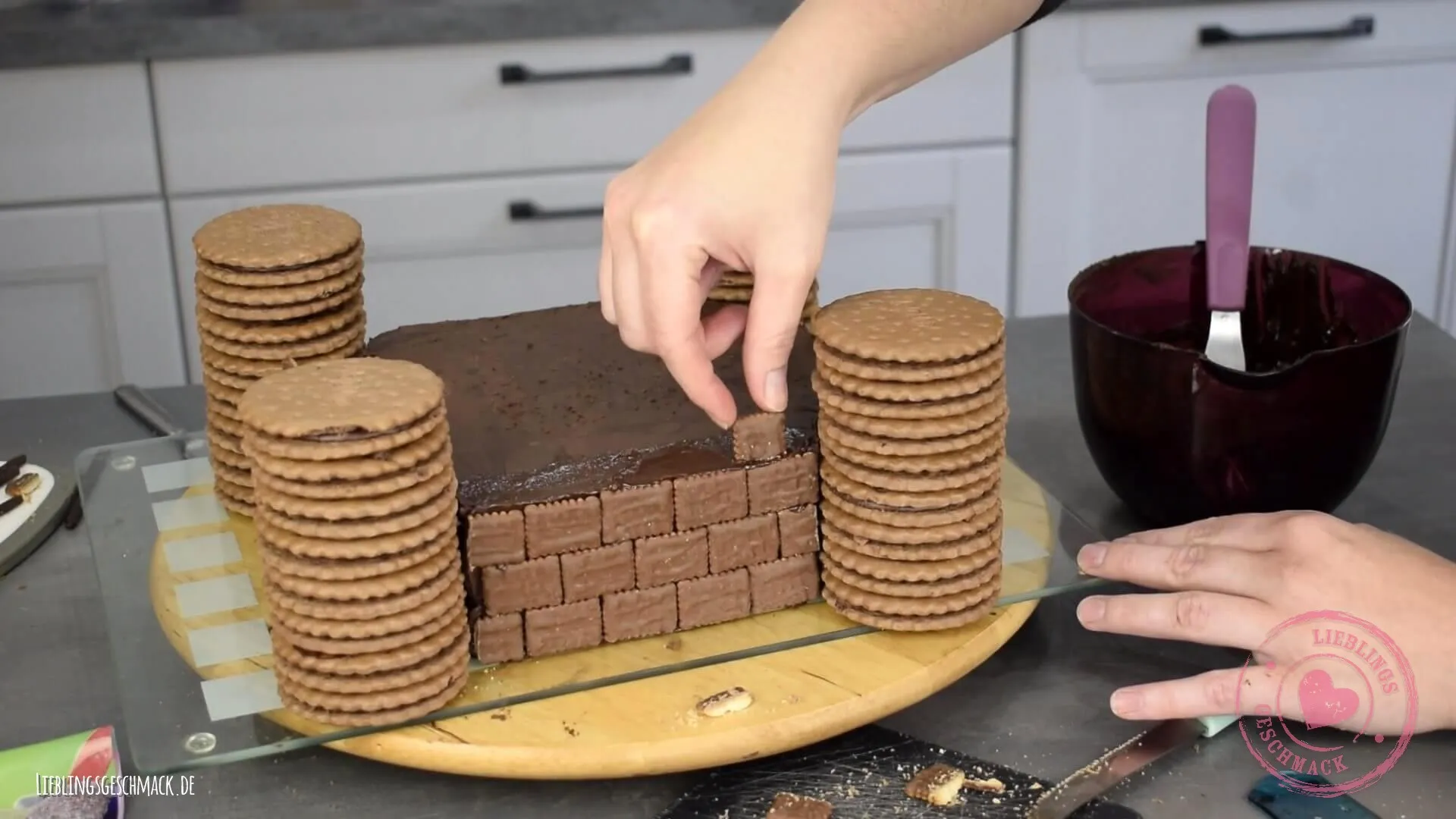 Die Ritterburg Torte wird mit kleinen Schokokeksen verkleidet, um eine Ziegelmauer-Optik zu erzeugen