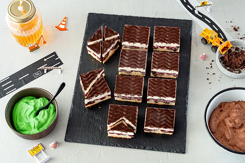 Donauwellen-Blechkuchenstücke werden für die Form zugeschnitten