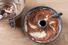 Dunkler Kakao-Teig wird über den hellen Teig gegeben und marmoriert