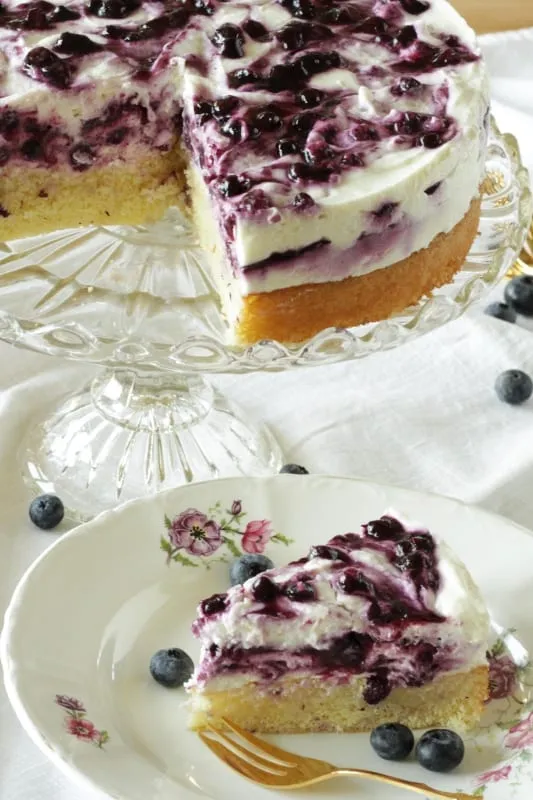 Ein angeschnittenes Stück Blaubeer-Quark-Torte, das die Schichten zeigt