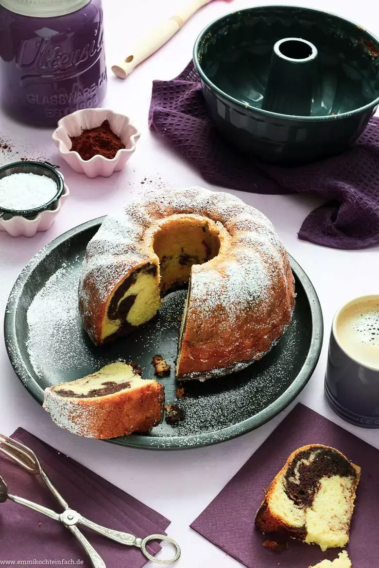 Ein aufgeschnittener Marmorkuchen auf einem Kuchenteller, der das charakteristische Marmormuster zeigt.