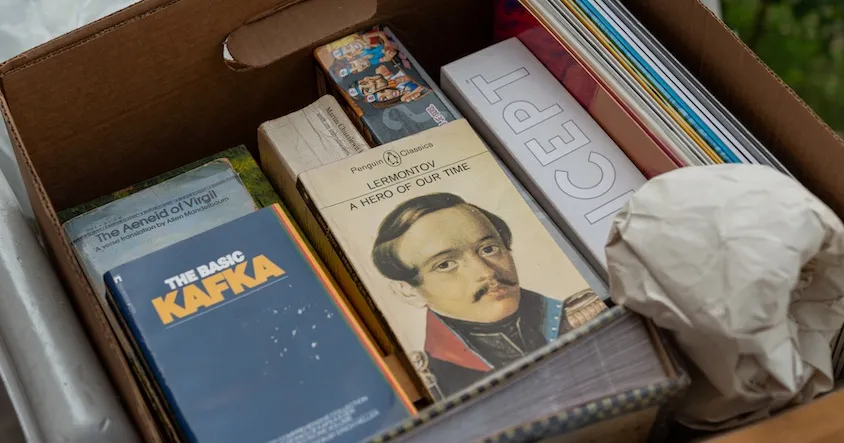 Ein Bild zeigt eine Hand, die ein Smartphone hält, auf dem das Amazon-Logo und Symbole für Geld, Suche und Planung zu sehen sind.