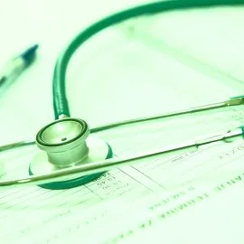 Ein bunter Stapel verschiedener Münzen und ein grüner Haken als Symbol für steuerlich absetzbare Vorsorgeaufwendungen